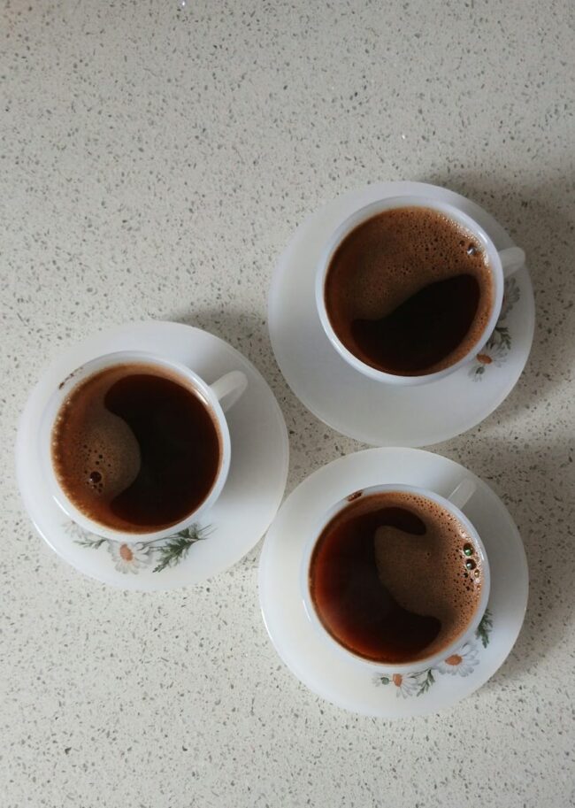 Three elegant Turkish coffee cups on saucers seen from above, showcasing a warm and inviting setting.