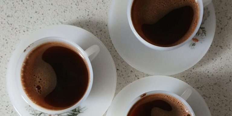Photo by Melike Baran Three elegant Turkish coffee cups on saucers seen from above, showcasing a warm and inviting setting.