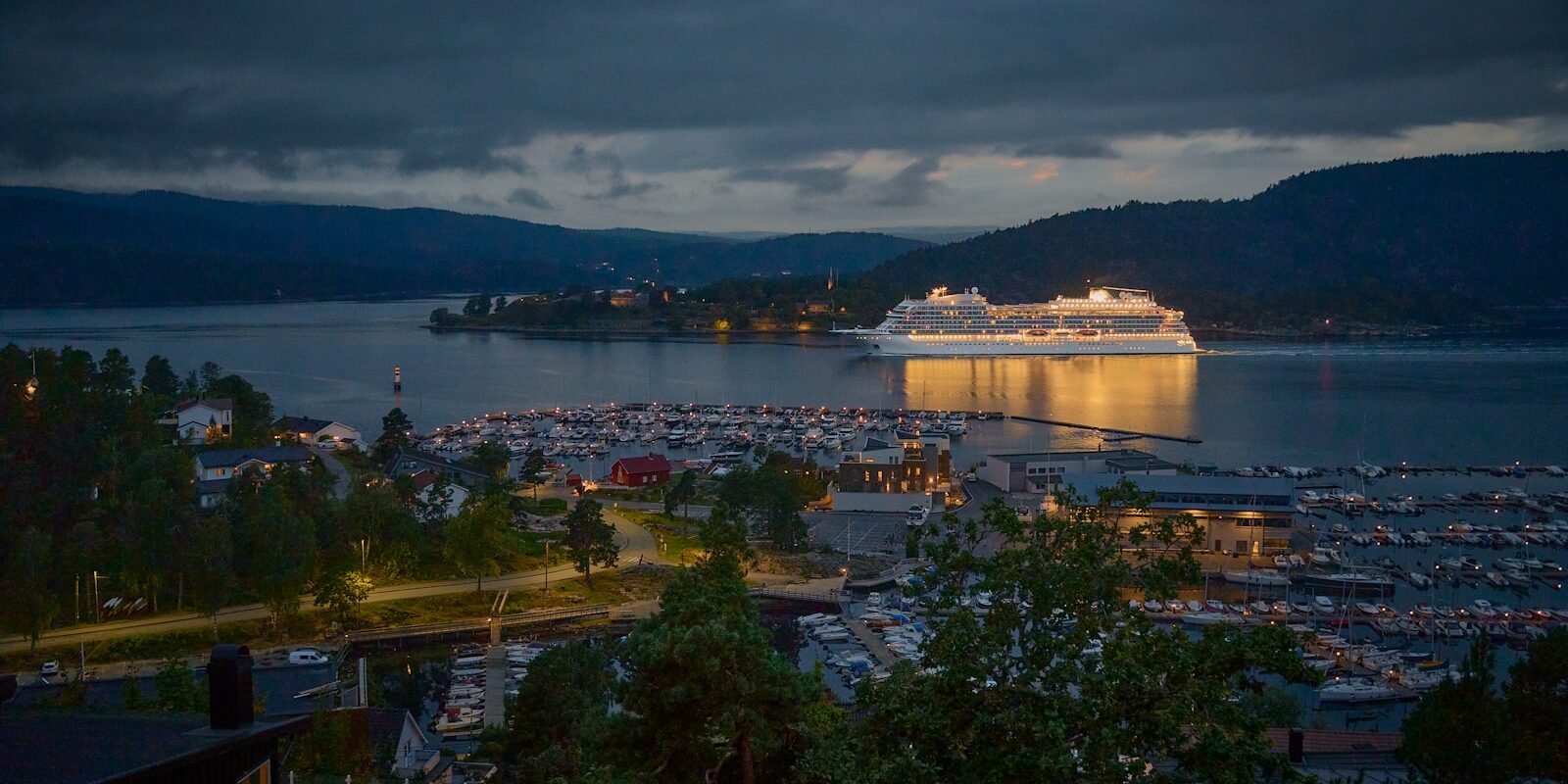 Photo by Vidar Nordli-Mathisen Large cruise ship docked in a harbor at dusk.