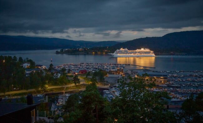 Large cruise ship docked in a harbor at dusk.