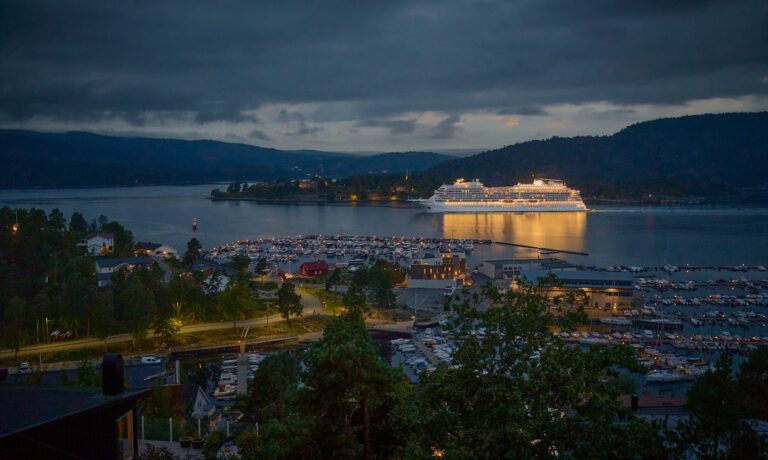 Photo by Vidar Nordli-Mathisen Large cruise ship docked in a harbor at dusk.